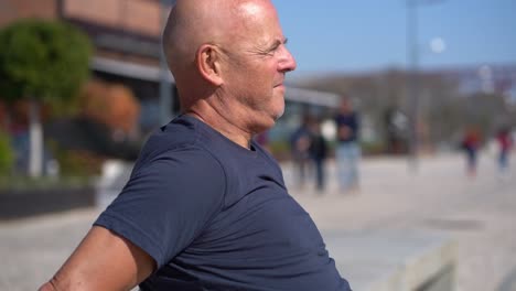 Profile-of-concentrated-bald-man-exercising-on-street